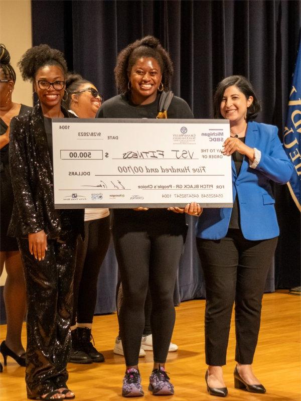 Valarie James accepts her $500 cash prize for receiving the People's Choice Award during the 2023 Pitch Black Competition.